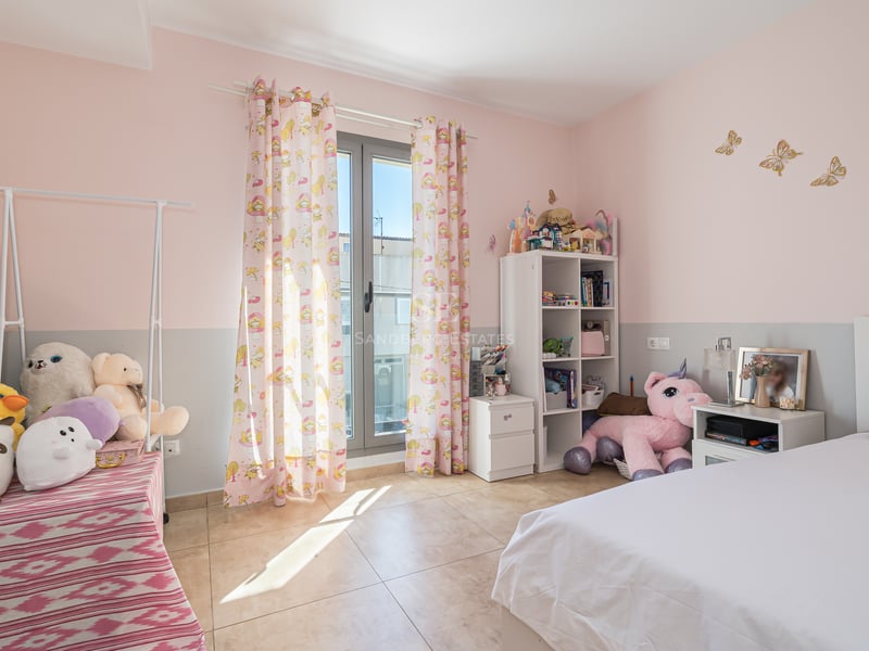 Rosa och grått barnrum med säng, gosedjur, hyllor och glasdörr ut till balkong.