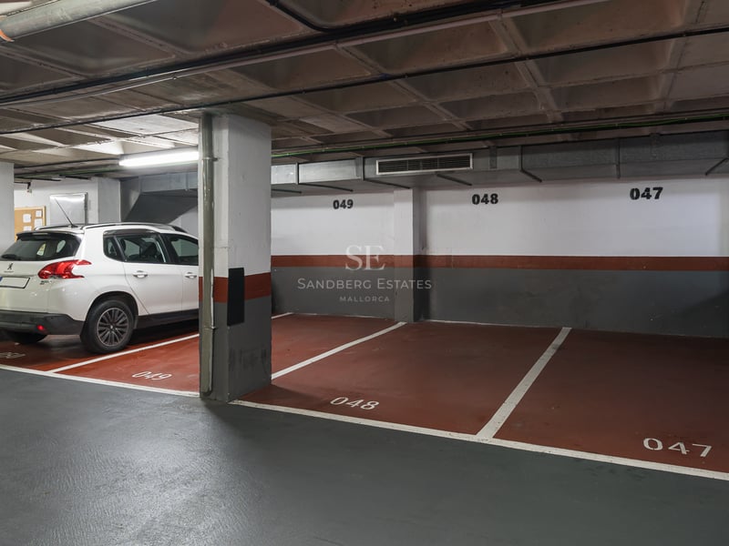 Inomhusgarage med numrerade platser och en vit SUV parkerad bredvid betongpelare.