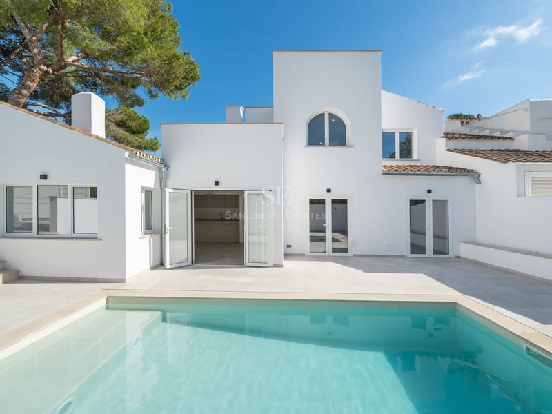Piscine turquoise devant une villa blanche moderne au style méditerranéen sous un ciel pur.