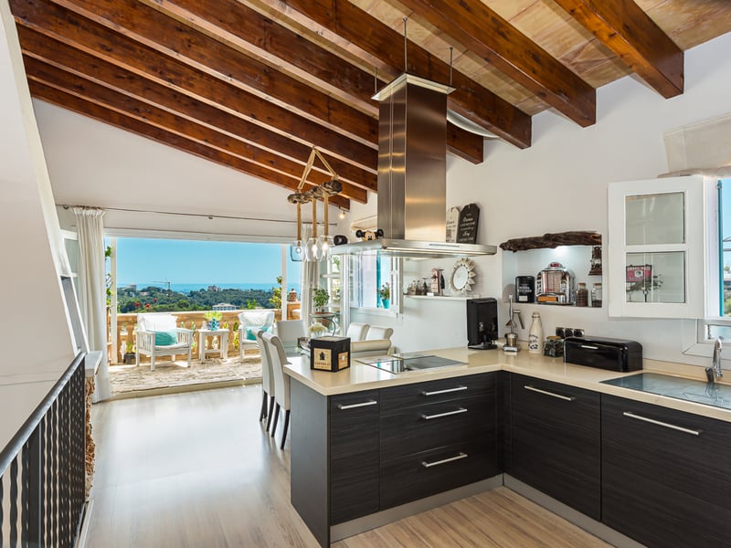 Spacious balcony with a sea view. Glass railing, light wood flooring, modern and elegant furniture. Bright and relaxing atmosphere.