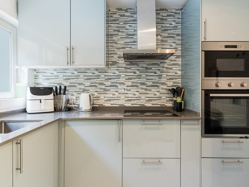 Cuisine moderne avec des armoires bleu clair, des plans de travail gris et une crédence en mosaïque.