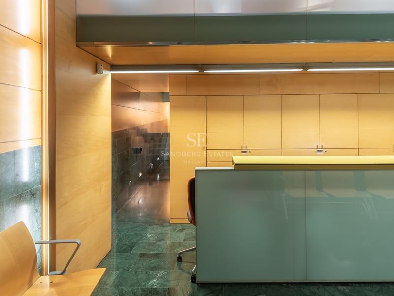 Bureau de réception moderne en verre dépoli, murs lambrissés en bois et sol en marbre vert foncé.