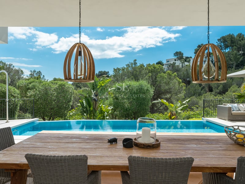 Extérieur d'une villa moderne avec piscine, espace de vie extérieur et végétation luxuriante. Design minimaliste et élégant.