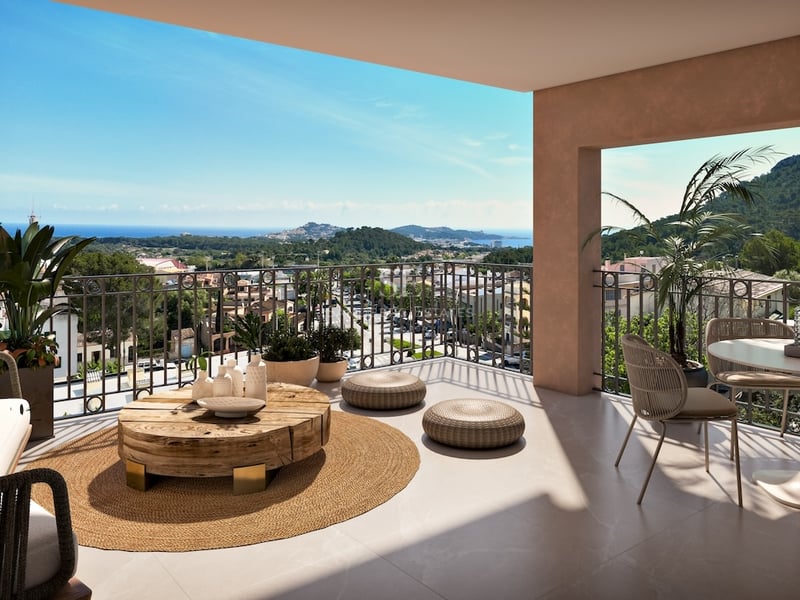 Spacious modern terrace with organic wood furniture and a jute rug overlooking a Mediterranean coastal town and sea.