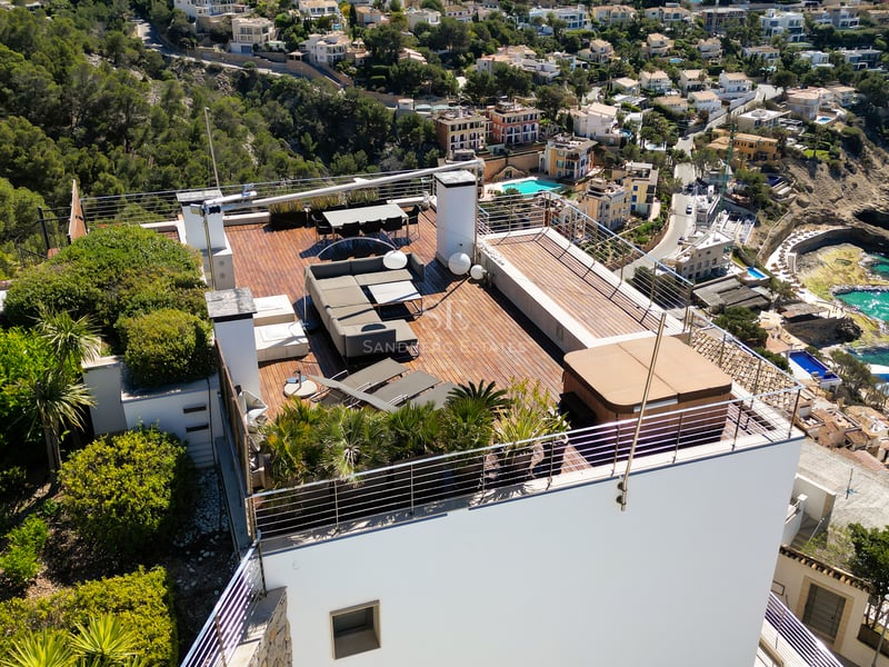 Aerial view of a modern rooftop terrace featuring wooden decking, a hot tub, lounge seating, and dining area.