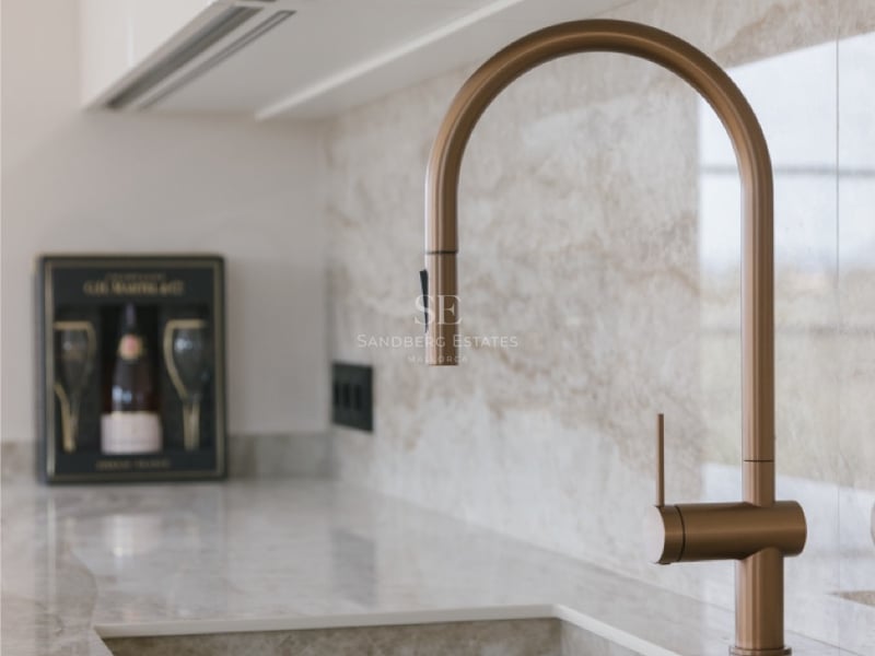 Nahaufnahme einer bronzenen Armatur auf einer Naturstein-Arbeitsplatte mit integriertem Spülbecken.