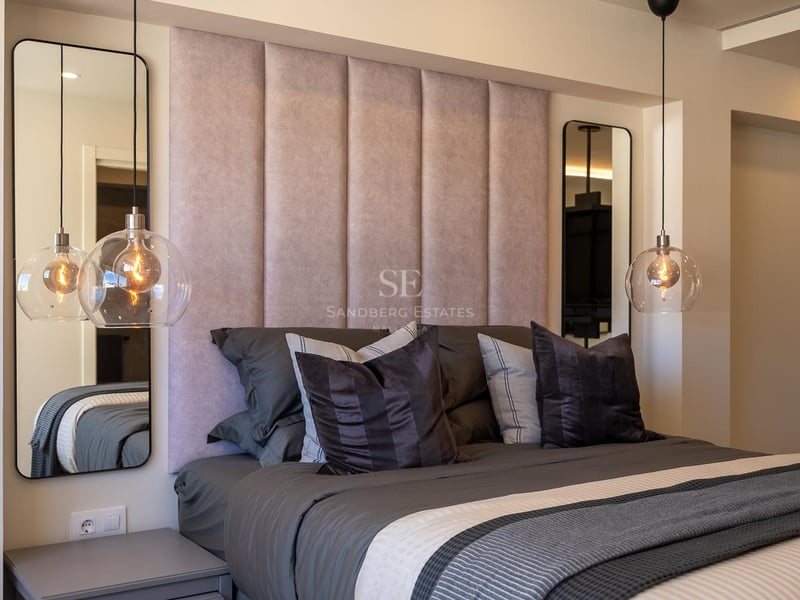 Bett mit rosa Kopfteil, hängenden Glaslampen und symmetrischen Spiegeln in einem modernen Luxusschlafzimmer.