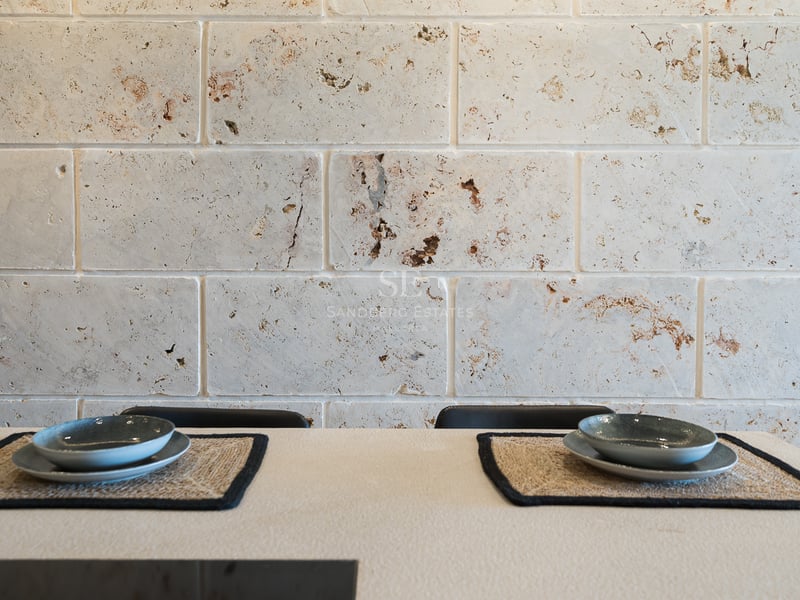 Gros plan d'un mur en blocs de travertin derrière une table avec des sets de table en fibres et bols en céramique.