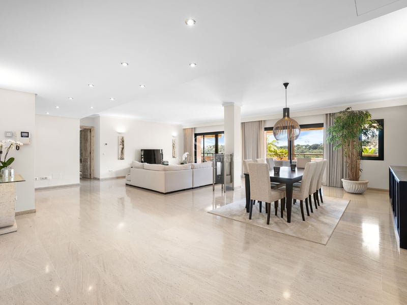 Intérieur lumineux à aire ouverte avec sols en marbre poli, un grand canapé blanc et une salle à manger moderne.