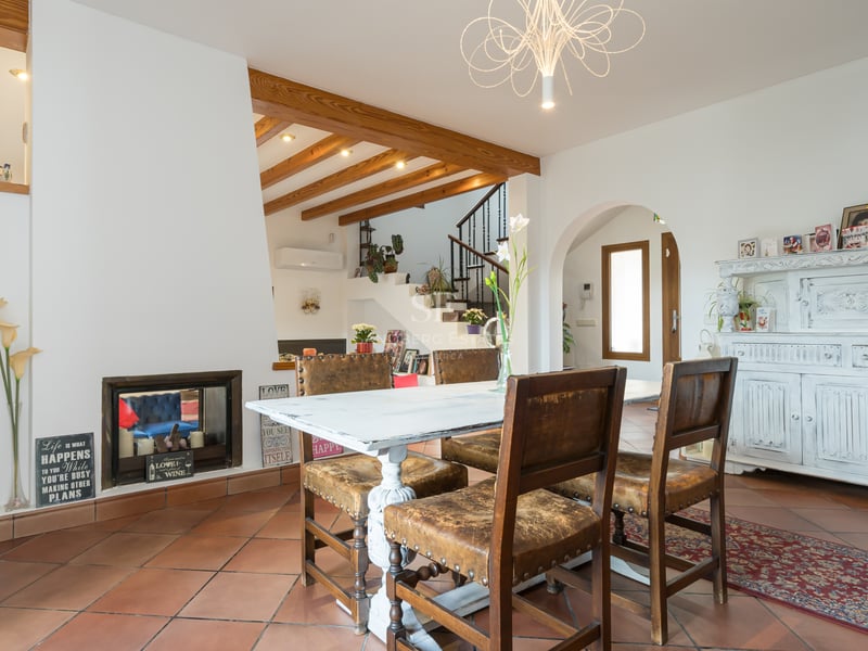 Interior dining room with terracotta floors, exposed wooden beams, white distressed table, and leather chairs.