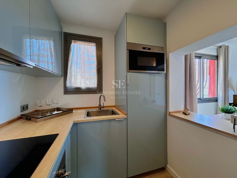 Modern kitchen with light blue cabinets, wooden countertop, stainless steel sink, and integrated microwave.