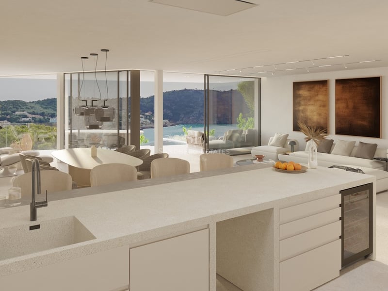 Großzügiges, offenes Wohnzimmer mit Küche, hängendem Kamin und großen Glasfronten mit Blick auf das Meer.