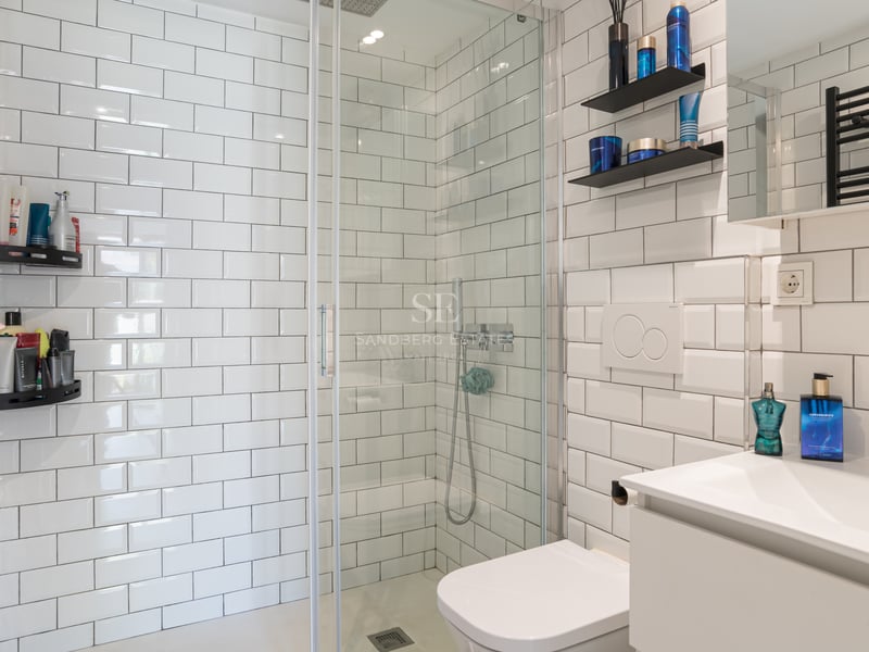 Salle de bains moderne avec carreaux de métro blancs, douche à l'italienne en verre et radiateur noir.