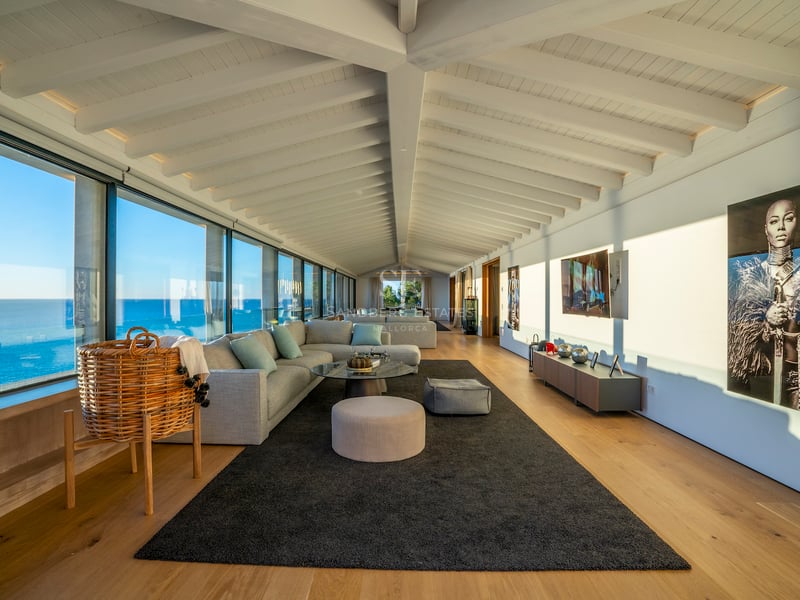 Zeitgenössisches Wohnzimmer mit weißen Holzbalkendecken, Eichenparkett und bodentiefen Fenstern mit Blick auf das Meer.