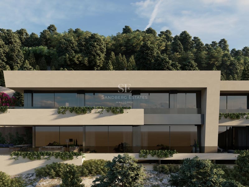 Vue de face d'une villa contemporaine à plusieurs niveaux avec de grandes baies vitrées et une façade couleur sable.