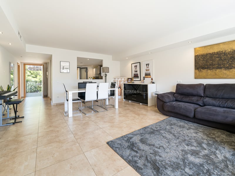 Rymligt vardagsrum med grå soffa, vit matgrupp, klinkergolv och utgång till solig terrass.