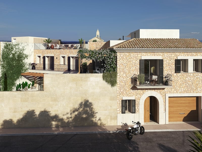 Vue extérieure d'une villa de luxe en pierre avec toit en terre cuite, entrée voûtée et terrasse sur le toit.