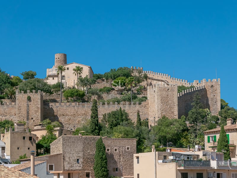Murs et tours en pierre d'une forteresse médiévale sur une colline sous un ciel bleu dans un village majorquin.