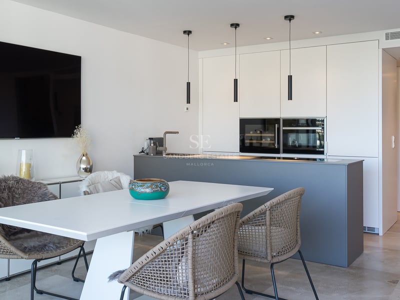 Moderne Küche mit grauer Kochinsel, grifflosen weißen Schränken und Essbereich mit Natursteinboden.