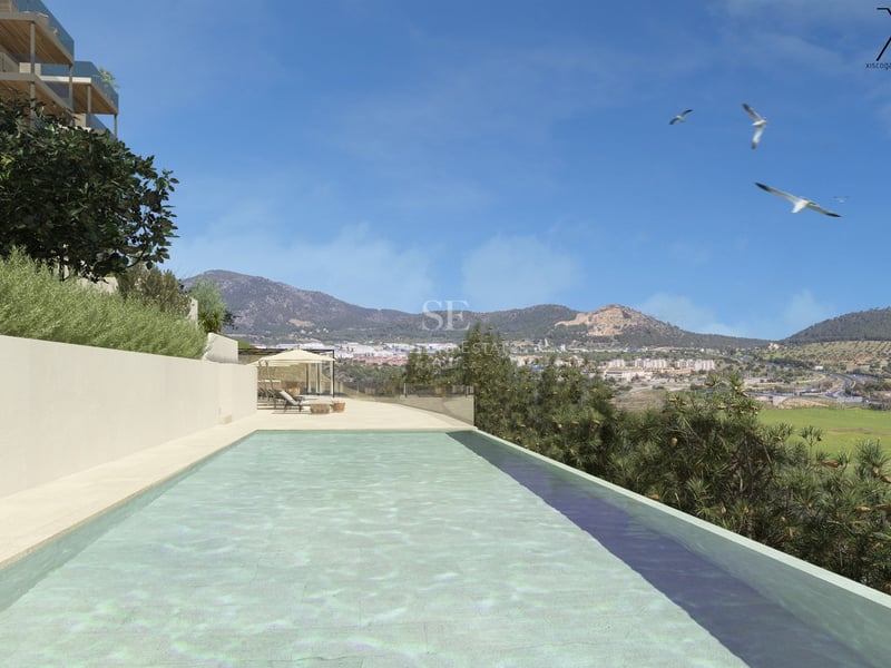 Une longue piscine à débordement turquoise surplombant une vallée de montagne sous un ciel bleu clair.