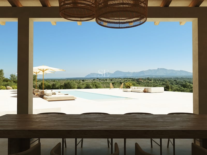 Une terrasse ombragée avec une table en bois sombre ouvrant sur une piscine et une chaîne de montagnes.