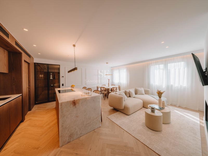 Salon à concept ouvert avec îlot en marbre, canapé beige et parquet en point de Hongrie.