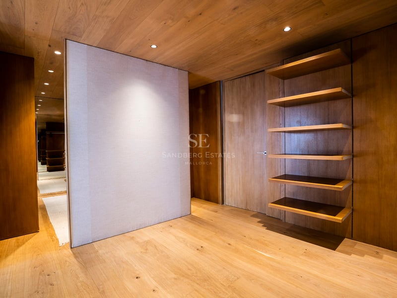 Minimalistisches Ankleidezimmer mit Wänden und Decke aus Eichenholz, Einbauregalen und warmer Beleuchtung.