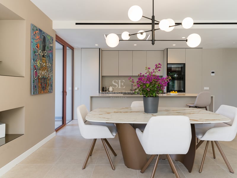 Contemporary dining room featuring a marble table, white chairs, and an integrated minimalist kitchen with pop art decor.