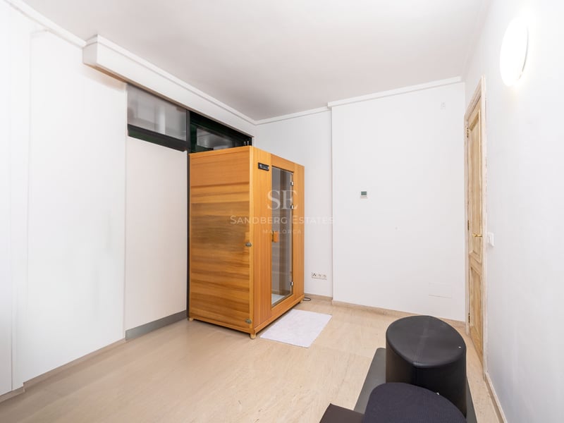 Pièce moderne blanche comprenant une cabine de sauna en bois autoportante et un sol en pierre claire.