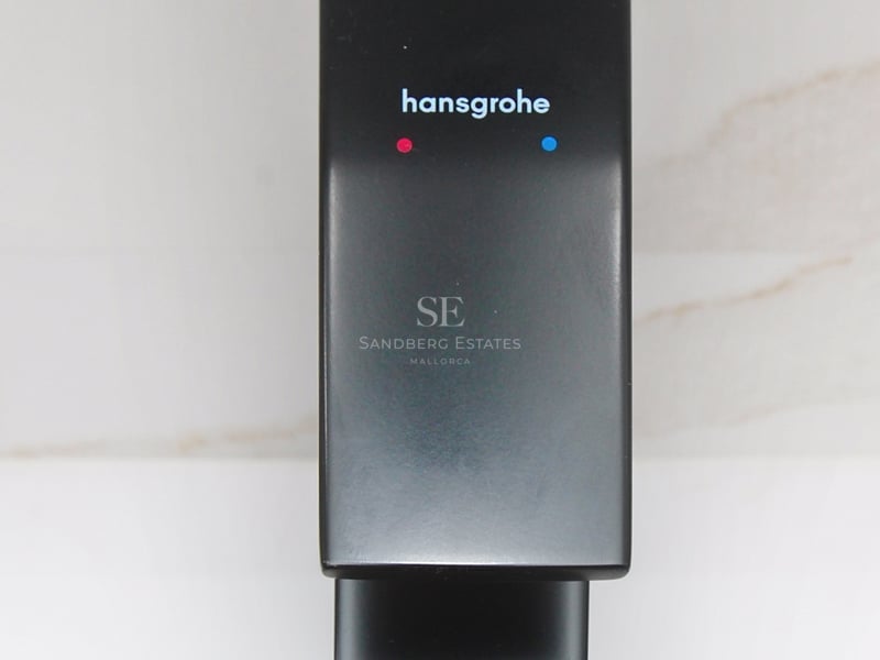 Närbild på en stilren mattsvart Hansgrohe-blandare mot en vit marmorvägg.