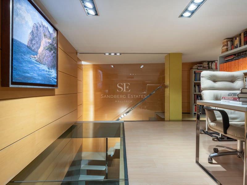Bureau moderne avec sol en verre sur escalier, boiseries en bois clair et bibliothèques intégrées.
