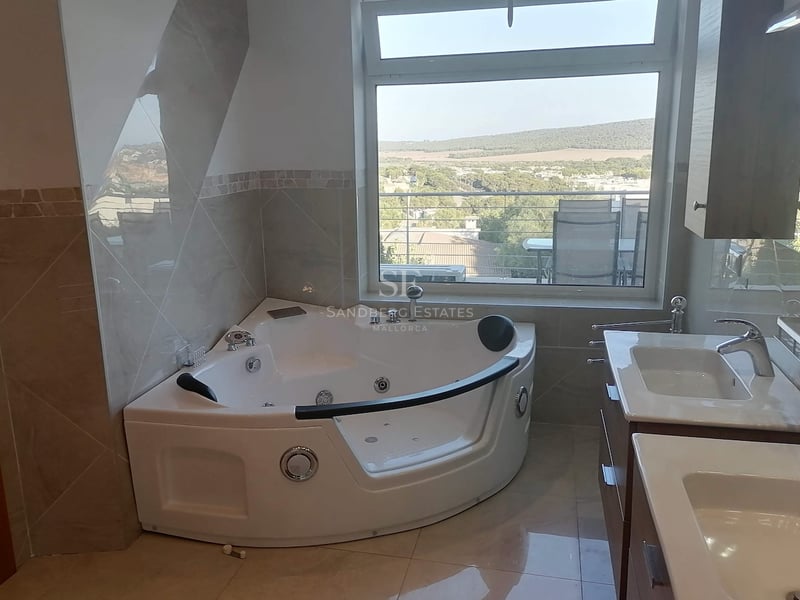 Salle de bains contemporaine avec baignoire balnéo d'angle, double vasque et vue sur la vallée verdoyante.