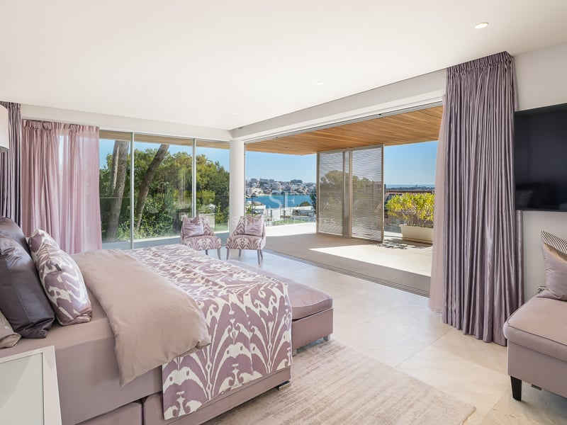 Helles Hauptschlafzimmer mit Doppelbett, zwei Sesseln und Zugang zur privaten Terrasse mit Blick auf die Küste.