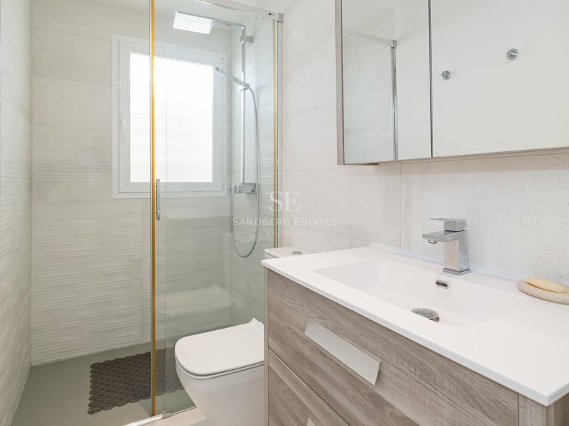 Bright bathroom featuring a wooden vanity, large mirror, and glass walk-in shower.
