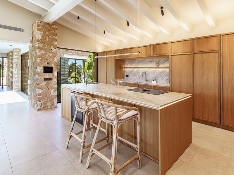 Moderne Küche mit Holzinsel, Marmor-Arbeitsplatte, Rattanhockern und weißer Balkendecke.