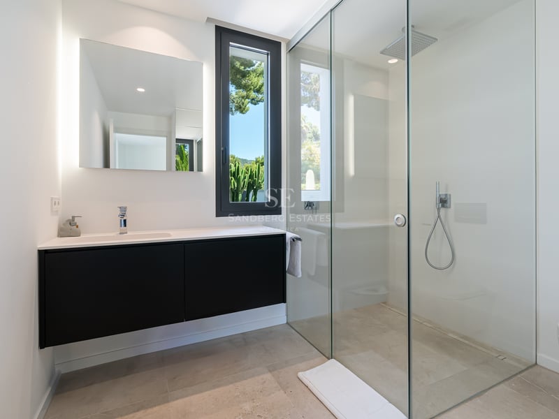 Salle de bains contemporaine avec douche à l'italienne en verre, meuble vasque noir et miroir rétroéclairé.