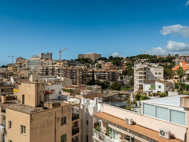 Weitwinkelblick auf die Skyline einer mediterranen Stadt mit Apartmenthäusern unter klarem blauem Himmel.
