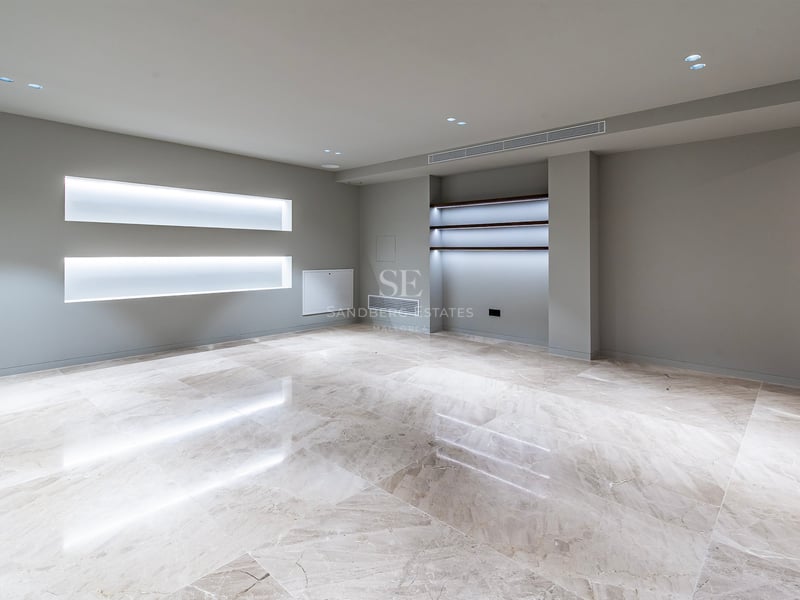 Pièce moderne vide avec sol en marbre poli, murs gris et éclairage LED intégré dans des niches murales.