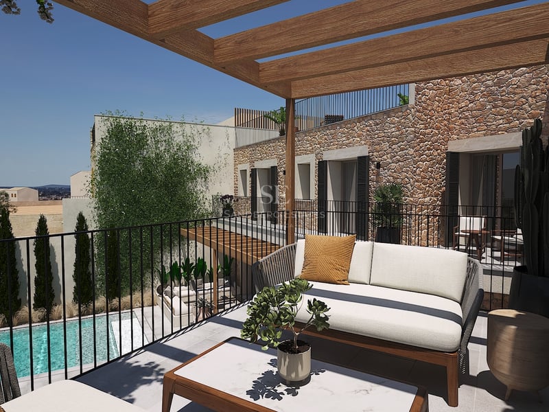 Terrasse contemporaine avec pergola en bois, canapé design et mur en pierre naturelle surplombant une piscine.