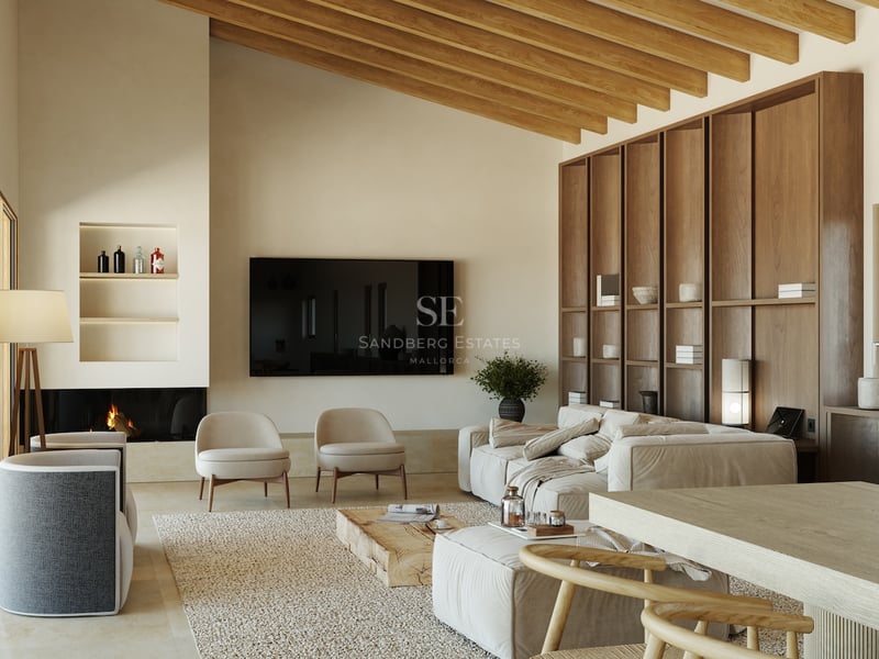 Salon spacieux avec de hauts plafonds à poutres apparentes, canapé en lin beige, bibliothèque en bois et cheminée.