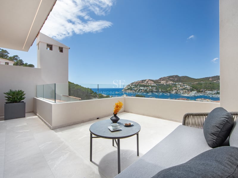 Terrasse de luxe avec garde-corps en verre, canapé extérieur et vue imprenable sur un port méditerranéen.