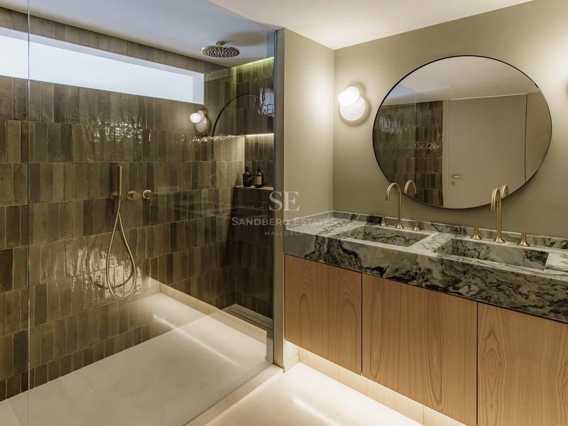 Modernes Badezimmer mit Glasdusche und Doppelwaschtisch aus Marmor mit goldenen Armaturen.