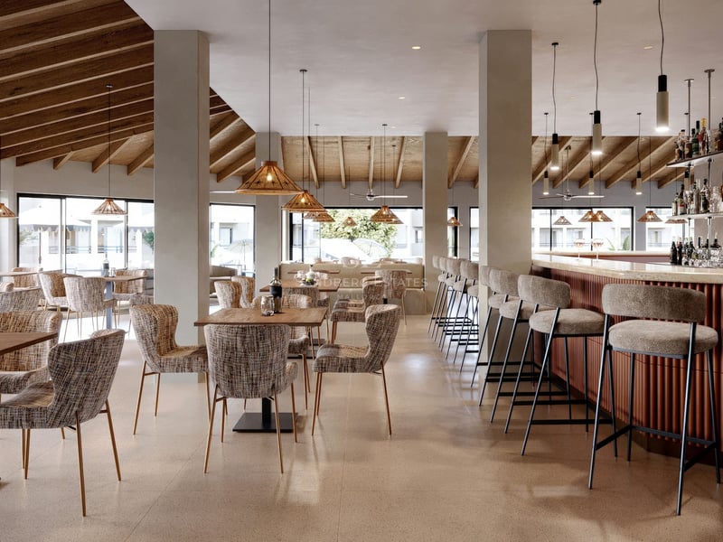 Intérieur d'un salon moderne avec plafonds en bois, suspensions, tables à manger et un bar avec tabourets hauts.