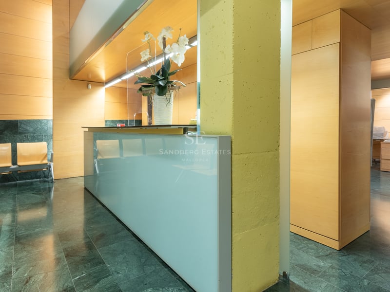 Hall d'entrée moderne avec bureau en verre dépoli, sol en marbre vert et murs en bois clair.