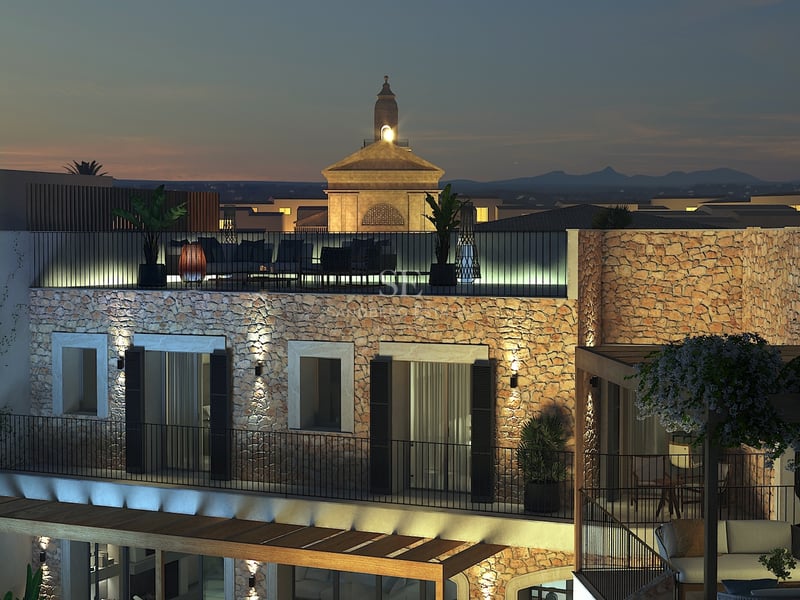 Vue nocturne d'une villa méditerranéenne avec murs en pierre éclairés et terrasse de toit dominant le village.