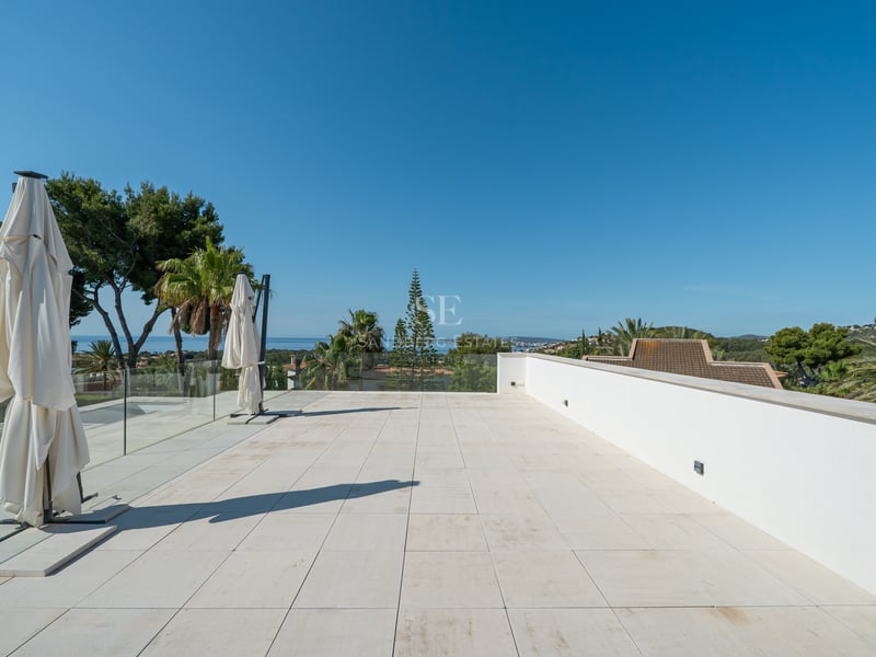 Grande terrasse en pierre blanche avec garde-corps en verre surplombant la mer Méditerranée.
