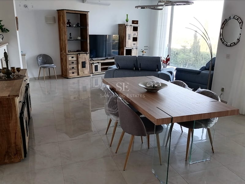 Grand salon et salle à manger avec carrelage poli, meubles en bois et table de repas avec pieds en verre.