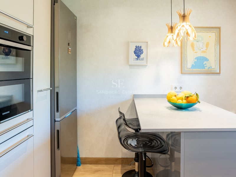 Samtida kök med Samsung dubbelugn, kylskåp i rostfritt stål och frukostö med svarta barstolar.