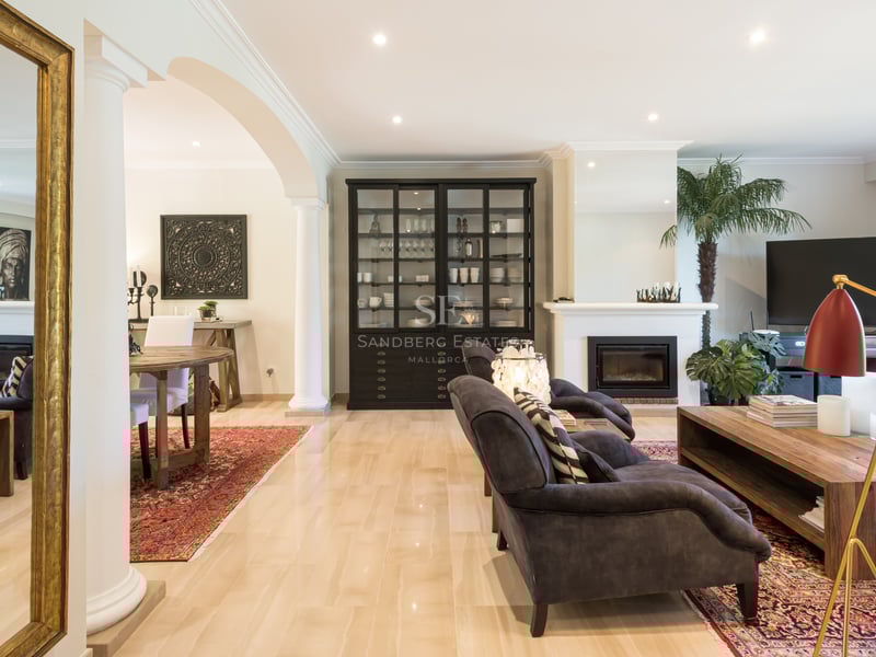 Spacious Mediterranean living room with marble floors, integrated fireplace, classical arches, and luxury furnishings.