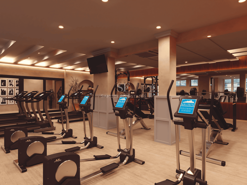 Salle de sport moderne avec tapis de course, vélos elliptiques, parquet et éclairage encastré chaleureux.